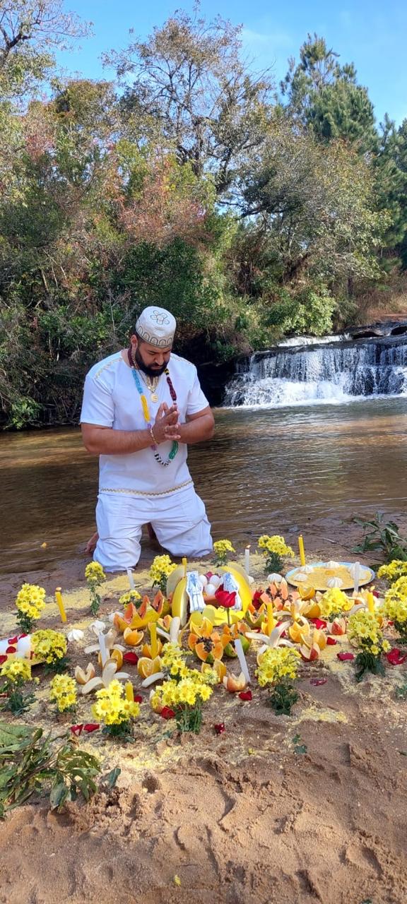 Pai Sebastian em oração na cachoeira com oferendas